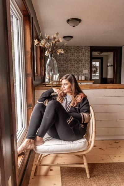 Cozy rattan reading chair by a sunny window beside the patterned-tile kitchen backsplash.