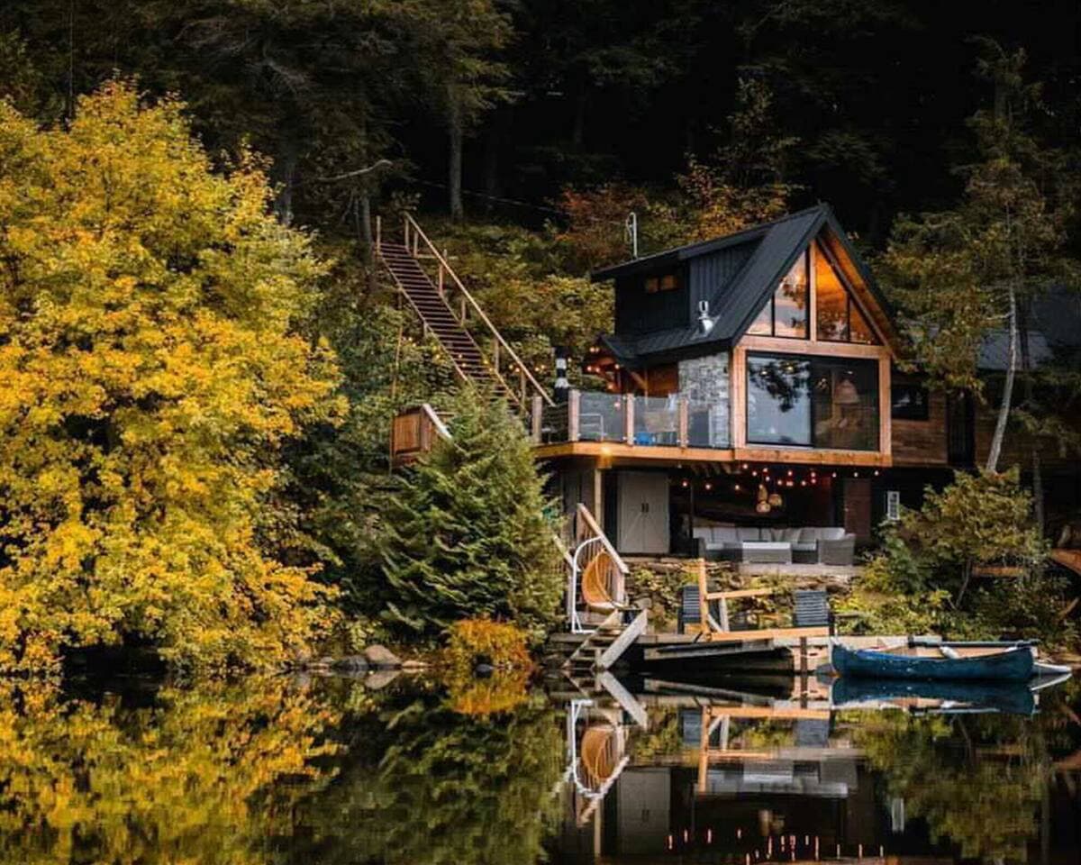 The Water's Edge treehouse glowing above the water amid golden autumn trees